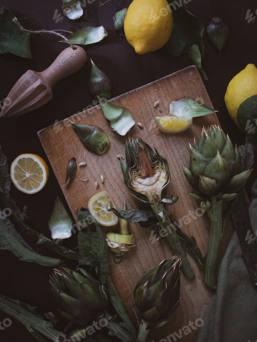 Preview: fresh cut artichoke and lemons on cutting board