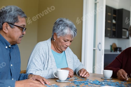 Preview: Two diverse female and male friends sitting at table and doing puzzles