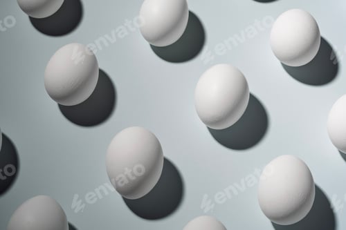 Preview: White eggs arranged on a light background with sharp shadows.
