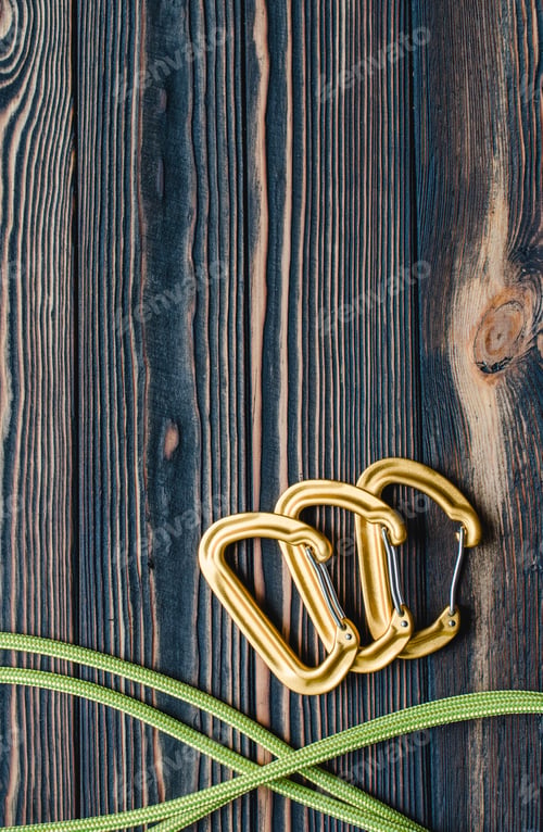 Preview: Isolated photo of climbing equipment. Parts of carabiners lying on the wooden table