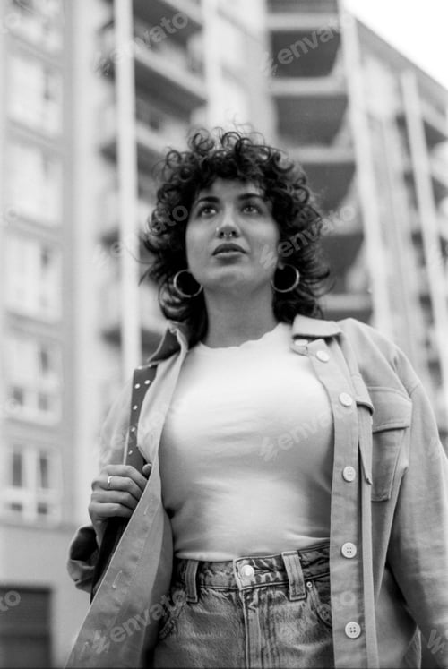 Preview: Young woman wearing casual clothes walking in urban setting, grainy black and white analog photo