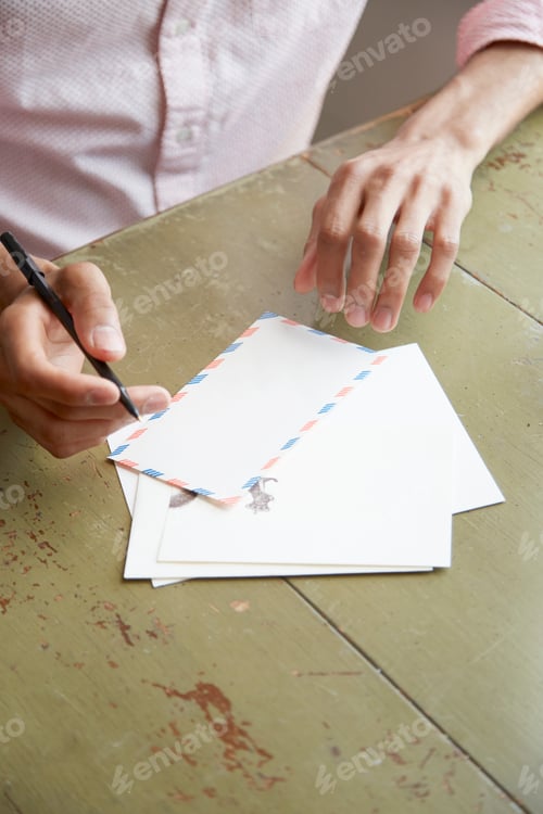 Preview: High angle view of young mans hands writing air mail letter