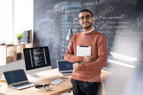 Preview: Young casual software developer with digital tablet standing by table