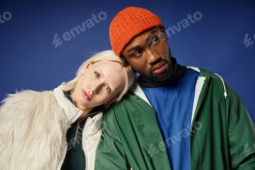 Preview: stylish multiethnic couple in winter attire, young woman in faux fur jacket and african american man