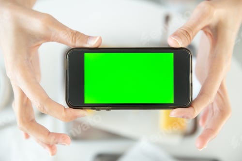 Preview: closeup hand holding smartphone top view in restaurant with blank space green screen colored