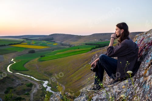 Preview: Handsome male model sitting on the rocks.