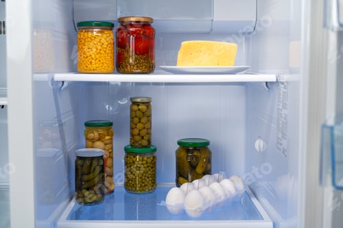 Preview: Glass jars of canned products on a fridge shelf
