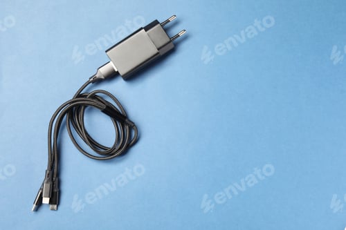 Preview: USB power adapter with triple charge cable on light blue background, top view. Space for text