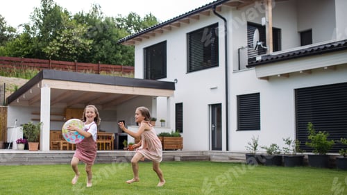 Preview: Two small girls sisters playing with a ball outdoors in the backyard, running