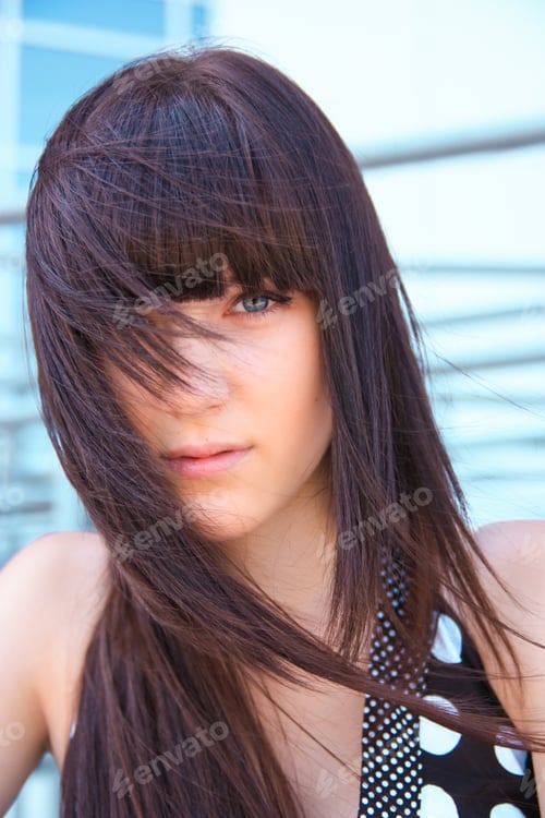 Preview: beautiful young brunette woman on the background of a modern building