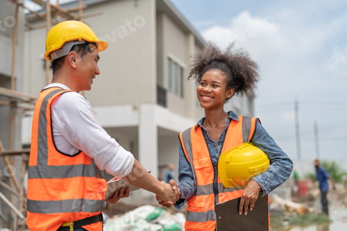 Preview: Happy female and male civil engineers shaking hands to work success project at construction site