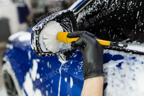 Preview: Hand brush washing car side mirror with foam in detailing service worker cleans mirror