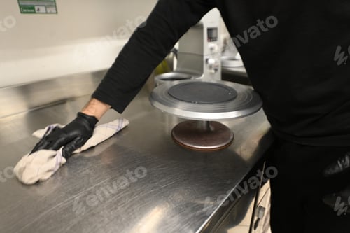 Preview: kitchen staff clean steel counter top in restaurant wearing gloves, hygiene concept