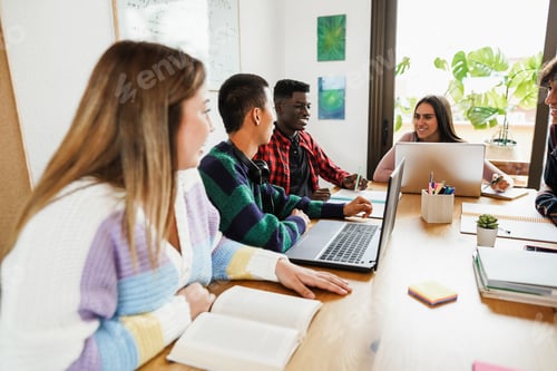 Preview: Multiracial students reading books and using laptop computers while studying at school library