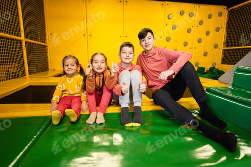 Preview: Four kids together sit at playground park. Sisters and brothers in active entertaiments.