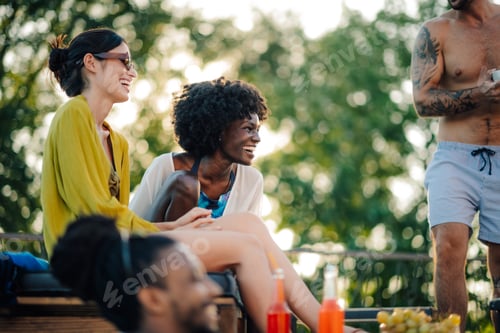 Preview: Friends enjoying drinks and laughing together at summer rooftop party