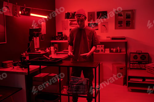 Preview: Man as Photographer Working in Darkroom Developing Photos