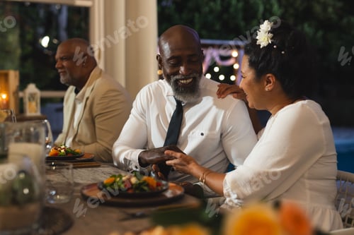 Preview: African American couple enjoying dinner and conversation at outdoor celebration