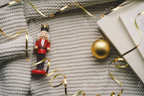 Preview: A nutcracker and golden ornament on a cozy knitted blanket during the holiday season