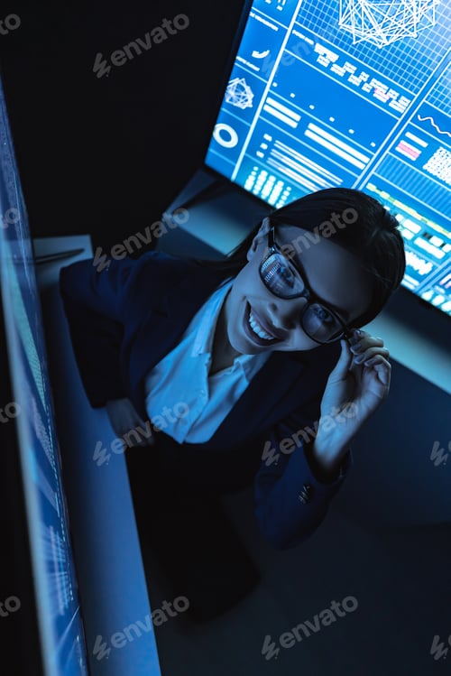 Preview: The smiling business lady works with sensor monitor in the dark office.