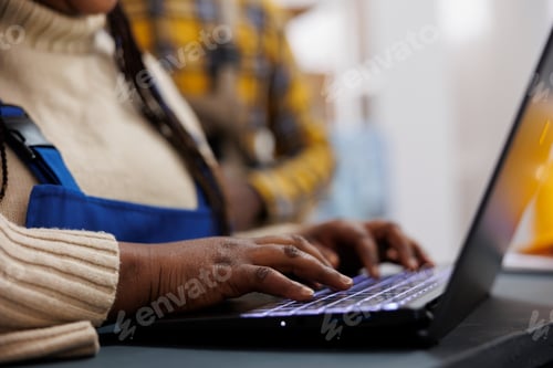 Preview: African american warehouse worker arms writing on laptop