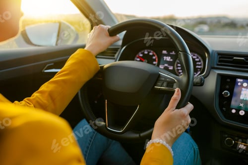 Preview: Close-up female hands in yellow suit driving car outside city