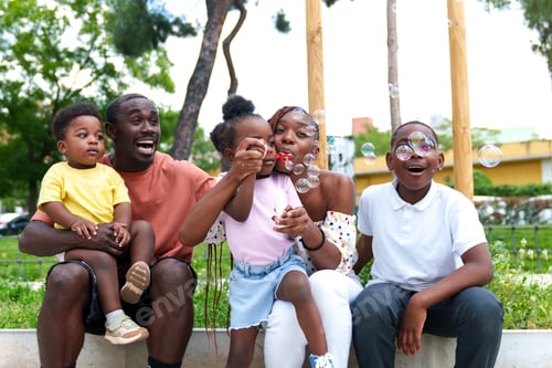 Preview: Joyful African Family in Colorful Park, Watching Their Daughter's Bubble-Blowing Skills with Delight