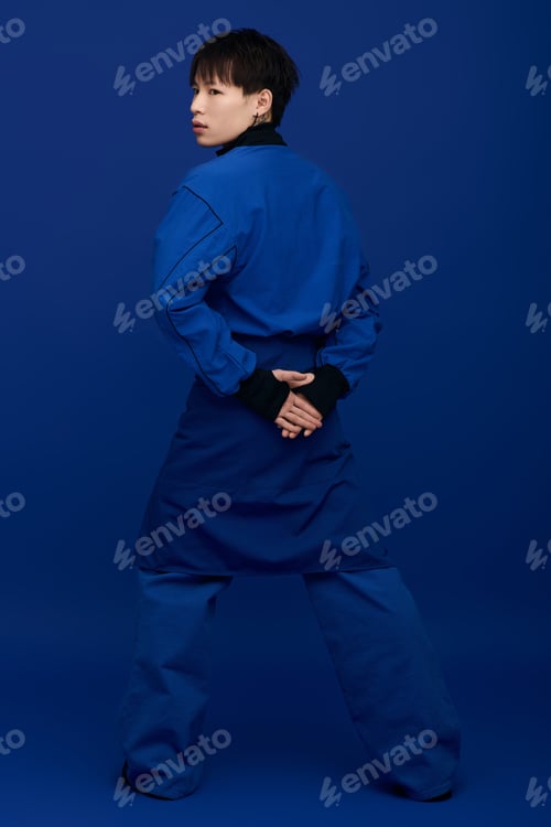 Preview: Young Asian man poses confidently in stylish clothing against a vibrant blue background