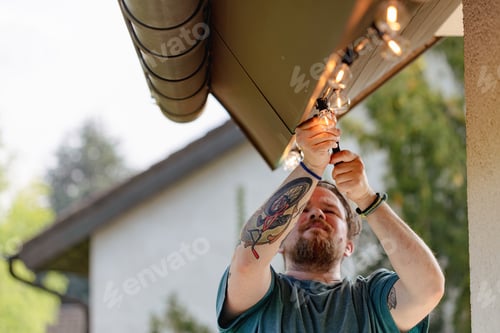 Preview: A man with tattoos performs household duties, installs lighting on the terrace, selective focus