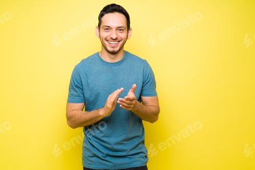 Cheerful Man Smiling and Clapping on Yellow Background