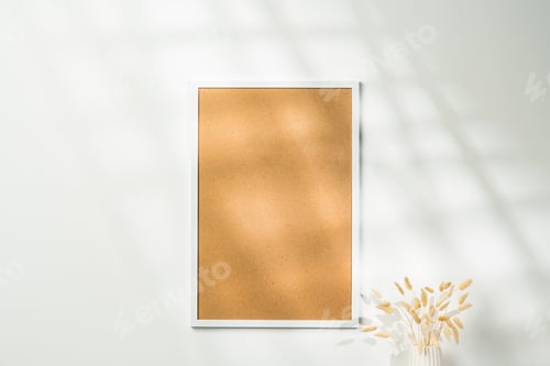 Preview: White blank photo frame with dry flowers in vase against white wall