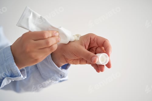 Preview: Hands in a blue shirt hold a tube of cream.