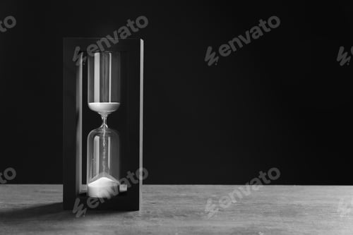 Preview: Hourglass with flowing sand on table against black background. Time management