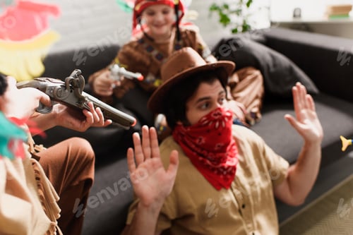 Preview: man in hat and red bandana playing together with sons in indigenous costumes at home