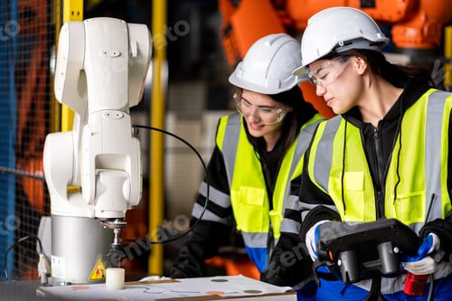 Preview: A team engineers meeting to inspect computer-controlled steel welding robots.