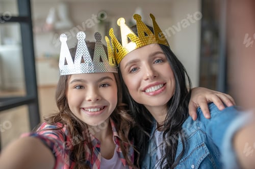 Preview: Mom and daughter wearing crowns and smiling