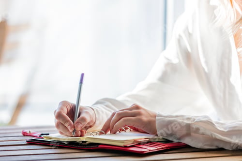 Preview: hand with pen writing something in to a notebook