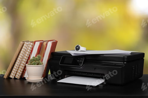 Preview: Stack of books and home printer against blurred background