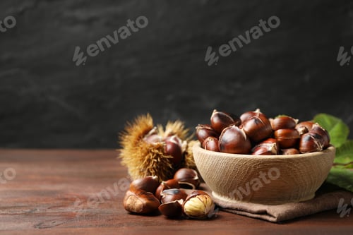 Preview: Delicious roasted edible chestnuts in bowl on wooden brown table. Space for text
