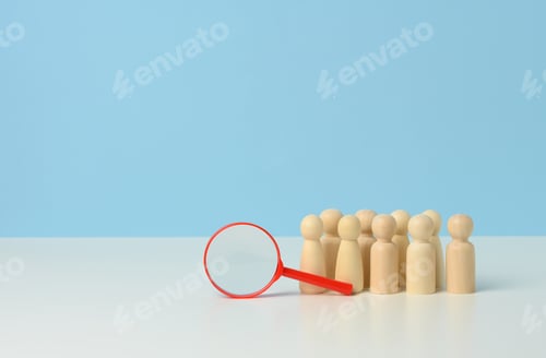Preview: Wooden figures of men stand on a blue background and a red plastic magnifying glass.