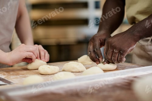 Preview: Close up of two people preparing fresh buns in bakery and working with dough