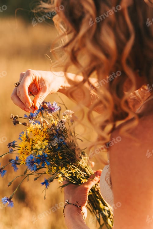 Preview: Woman Arranging Wildflower Bouquet in Rural Setting