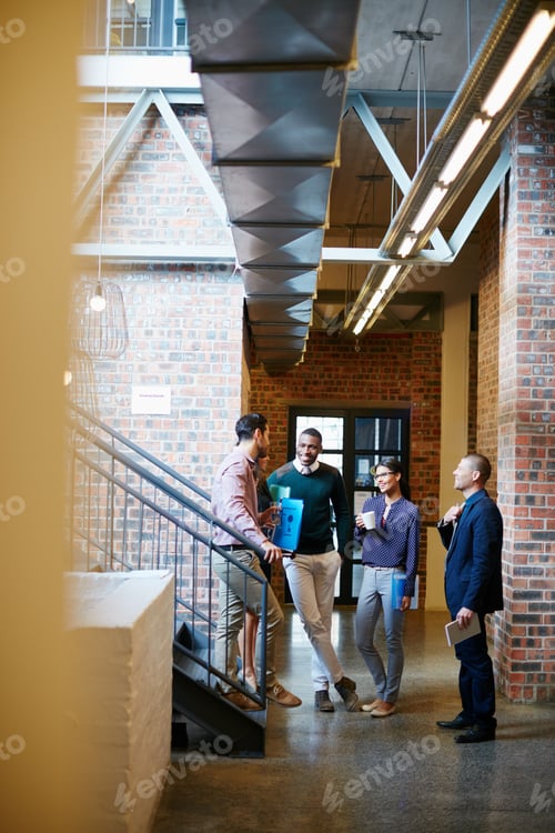 Preview: Shot of a group of businesspeople having a discussion in the hallway