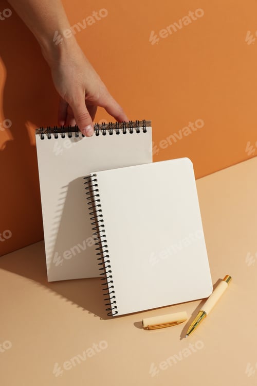 Preview: Open notebooks stand with pens on a light background