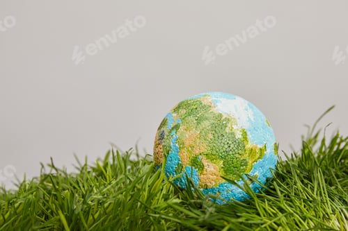 Preview: planet model placed on green grass surface, earth day concept
