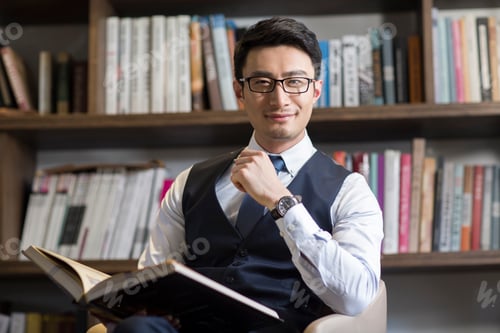 Preview: Young businessman reading book in his study