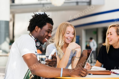 Preview: Happy multiethnic friends studying at table in cafe