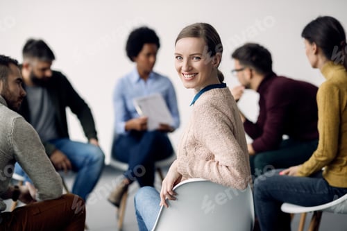 Preview: Young happy woman attending a group therapy at medical center.