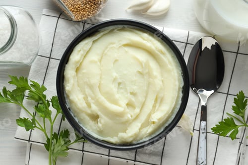 Preview: Mashed potatoes in bowl on towel, spoon and spices on white background, top view