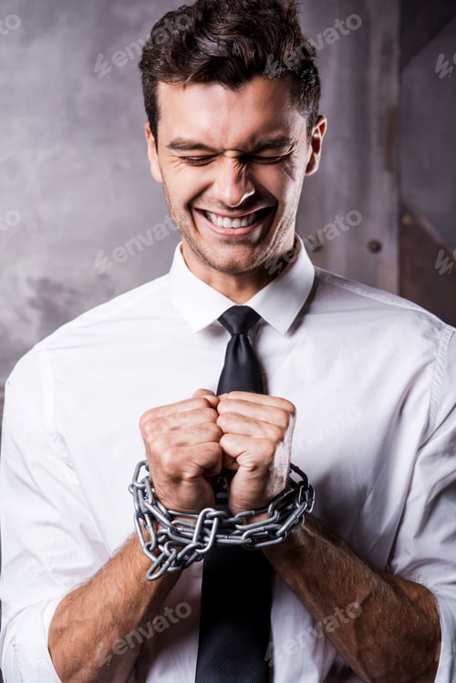 Preview: Businessman trapped in chains. Frustrated young businessman grimacing while being trapped in chains